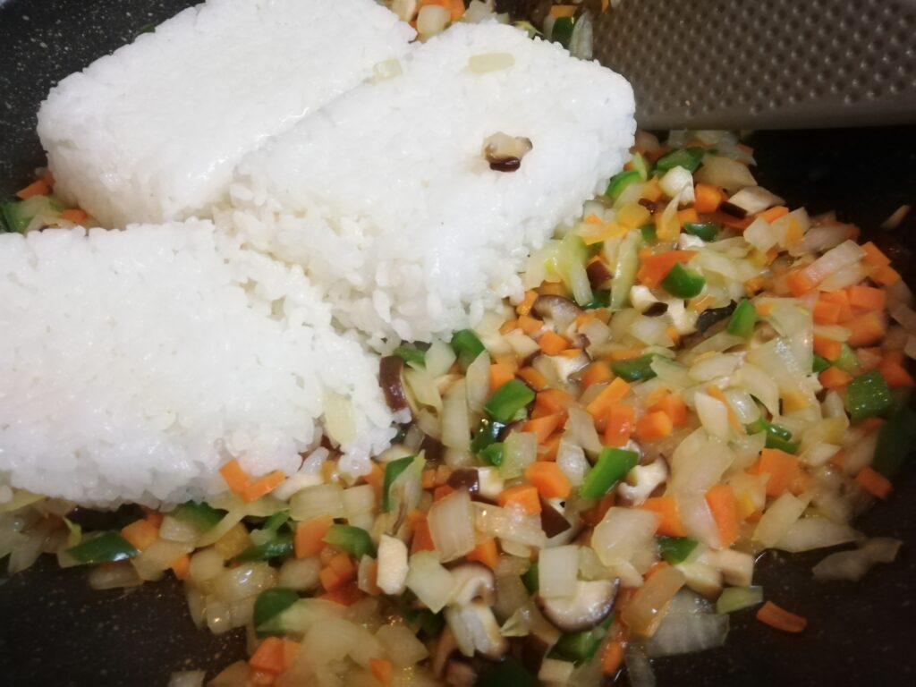 塩鶏の汁を使って炒めた野菜にごはんを加える、オムライス作り